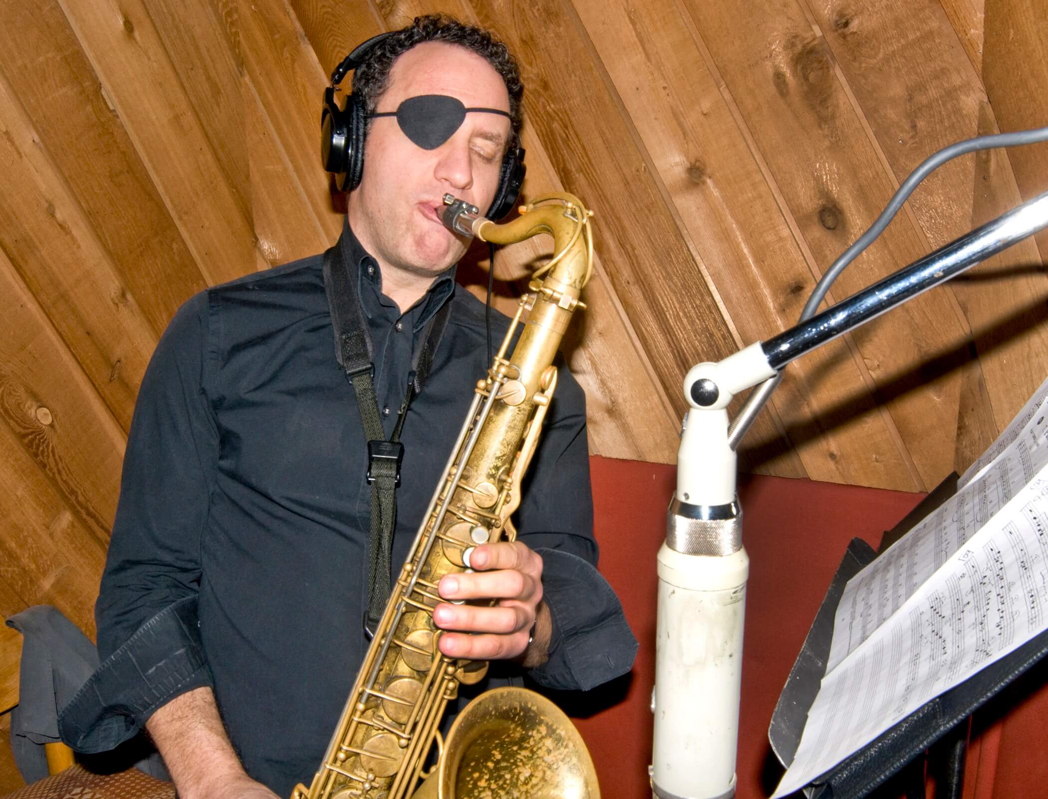 A man wearing headphones and playing the saxophone.