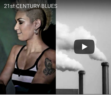 A woman with a tattoo on her arm and smoke stacks in the background.