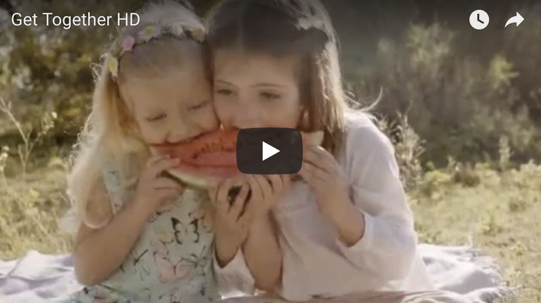 Two little girls eating watermelon together outside.